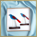 Decorative wall art of two blue and red birds on a light blue fabric background