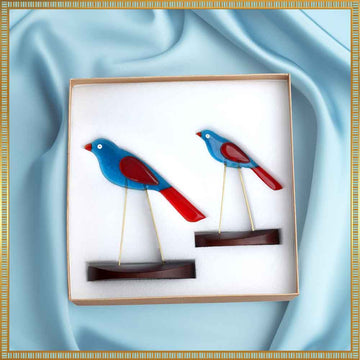 Decorative wall art of two blue and red birds on a light blue fabric background