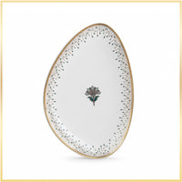 An oval white porcelain plate with a gold rim, decorated with a central floral motif and delicate black dotted lines around the edge, shown on a white background with a thin gold border.