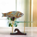 Decorative fish glass decor on a stand with a blurred indoor background