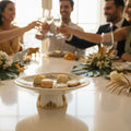 People toasting with glasses at a formal event, with a decorative plate of cookies in the foreground.