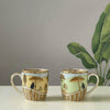 Two decorative mugs with artistic designs on a plain background