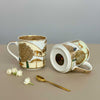 Two ceramic mugs with nature-themed designs on a neutral background