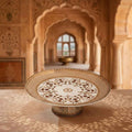 Decorative plate with intricate patterns on a pedestal in an ornate architectural setting