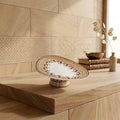 Decorative plate on a wooden stand against a tiled wall.