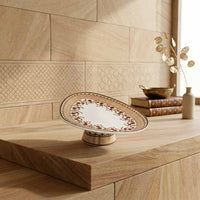 Decorative plate on a wooden stand against a tiled wall.