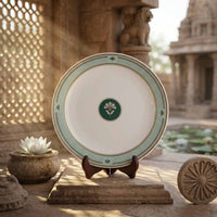 Decorative plate with a green emblem on a stand in an outdoor setting with architectural elements and water.
