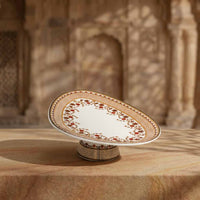 Decorative ceramic plate on a pedestal with intricate patterns, set against a warm-toned architectural background.