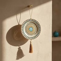 Decorative circular hanging ornament with tassel on a beige wall