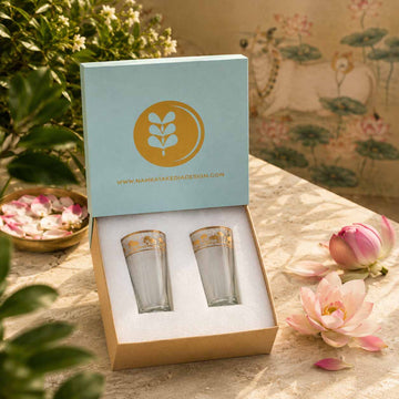 Two glass tumblers in a decorative box with a floral design in the background