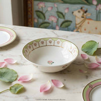Decorative ceramic bowl with floral patterns on a marble surface with flower petals.
