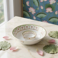 Set of white bowls with decorative patterns on a marble surface with lotus leaves and petals.