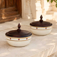 Two porcelain bowls with wooden lids on a stone surface.